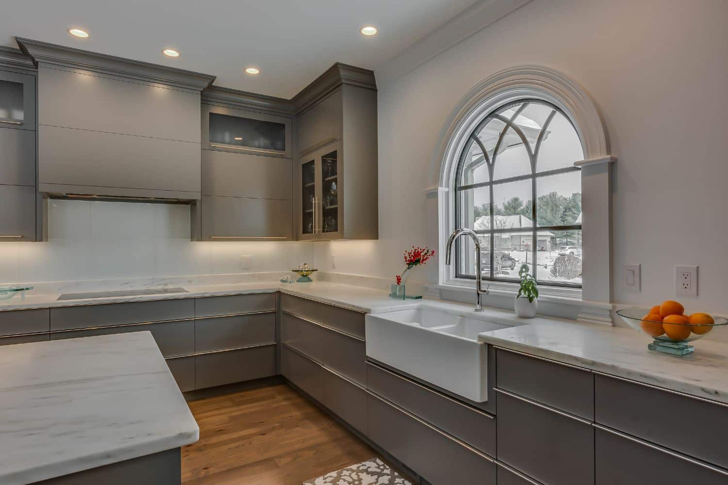 Custom kitchen in Granger Indiana with view of window and sink, gray cabinets and custom stove hood