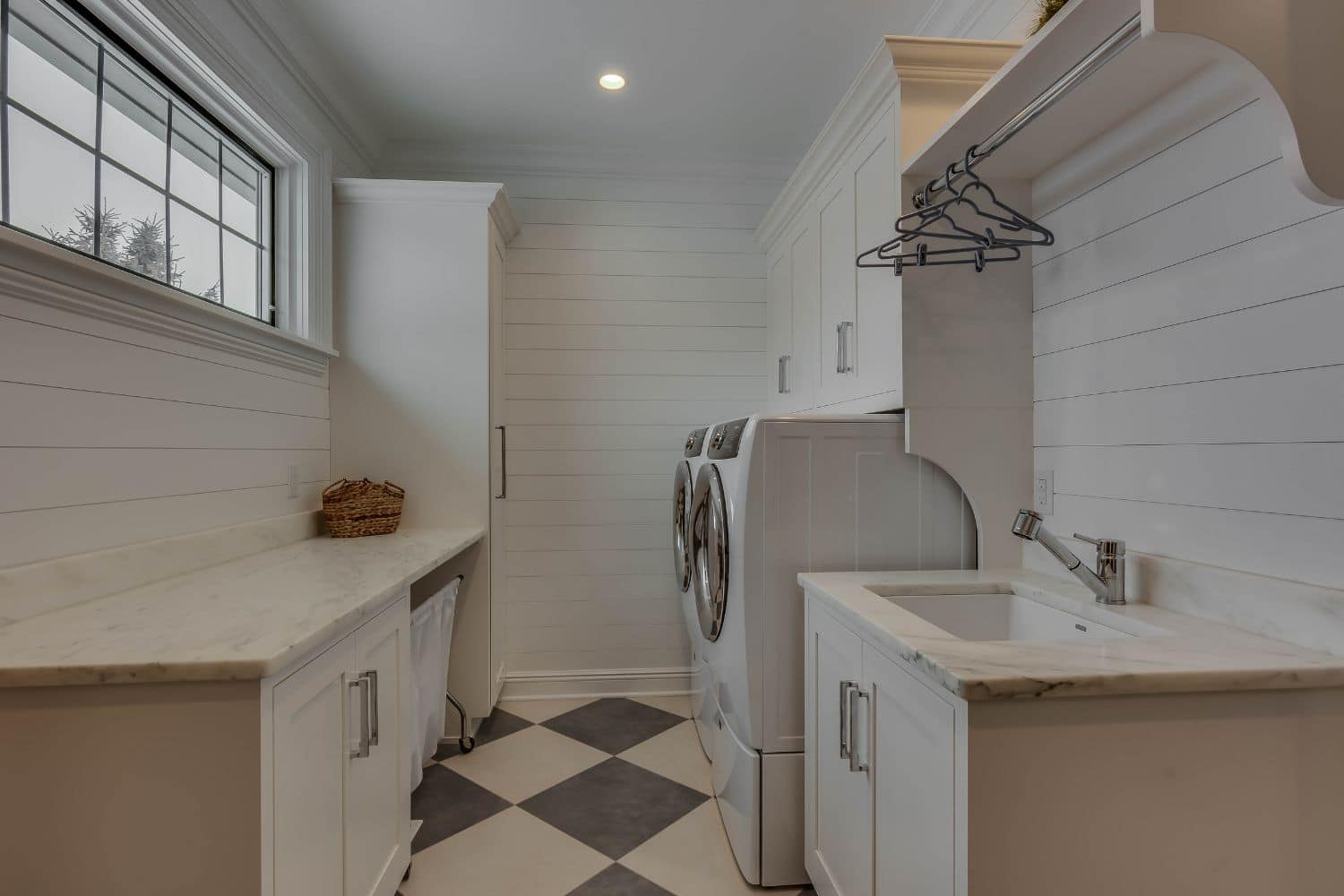 View of laundry room cabinets in Granger Indiana. White sink, walls, and counter