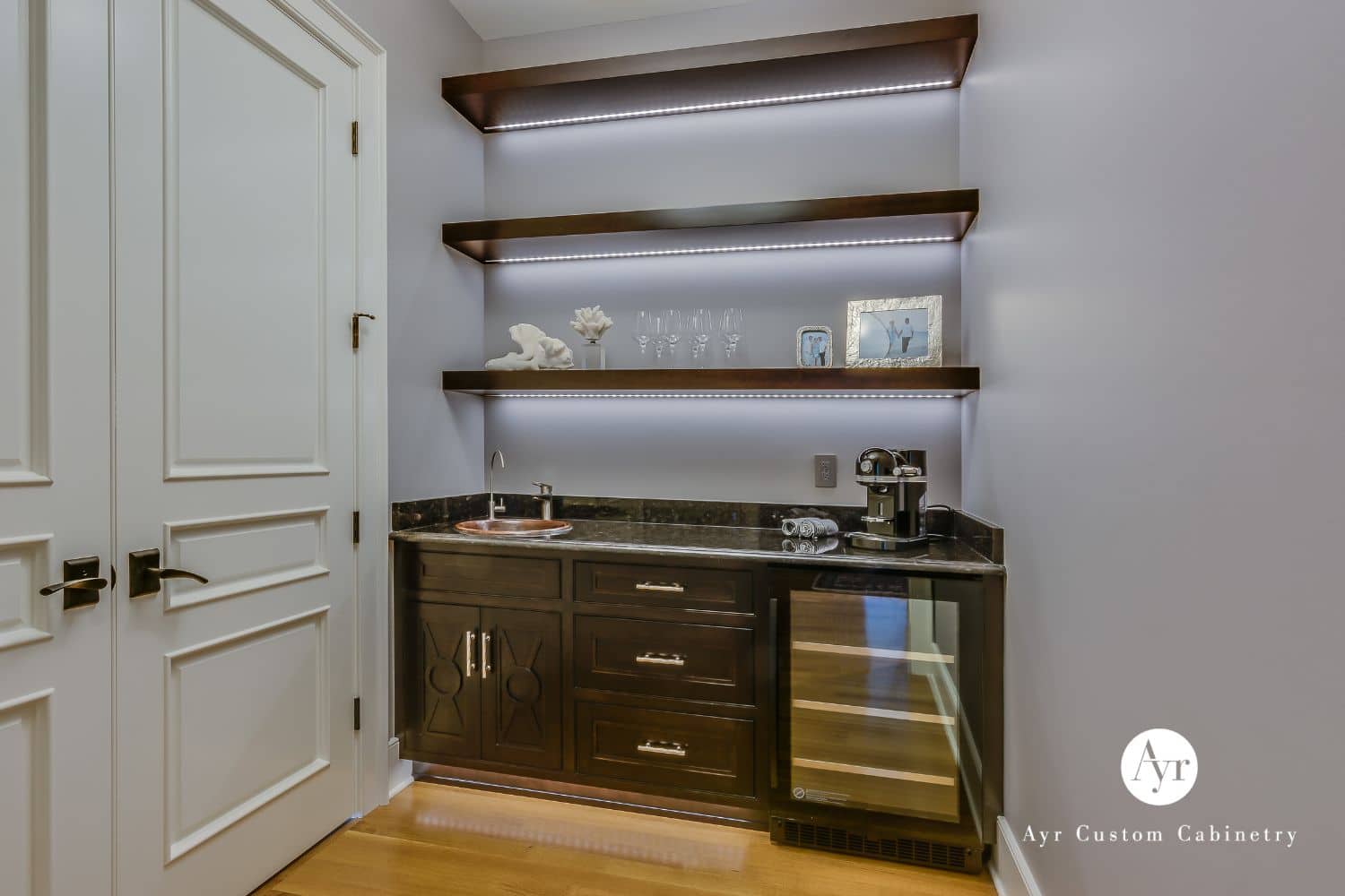 Wet bar cabinets, shelves, fridge against white door in Stevensville MI